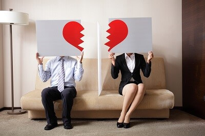 couple each holding half of a broken heart sign